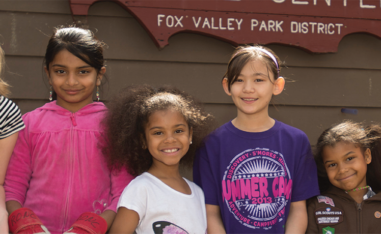 Group of smiling Girl Scouts outside Red Oak Nature Center