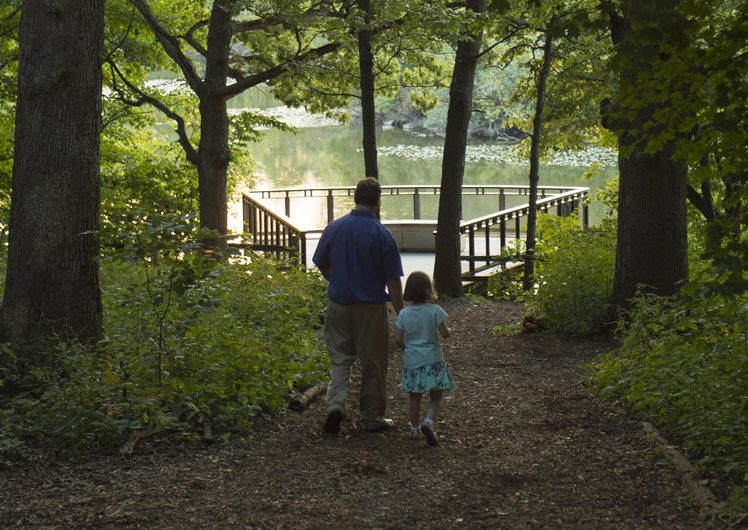 Man and daughter walking towards river dock