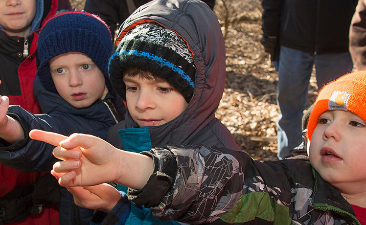 Kids putting finger up to maple tree to taste maple